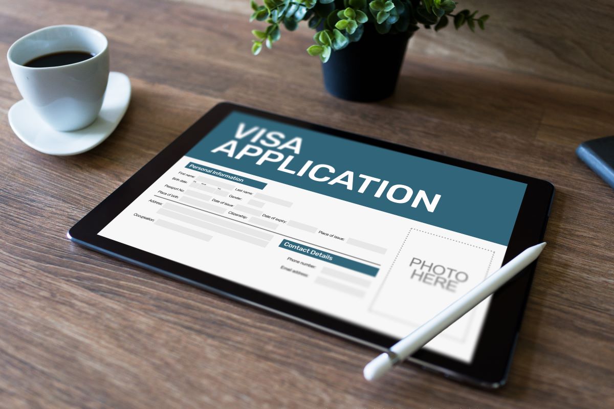ipad with online visa application on desk with coffee cup and plant